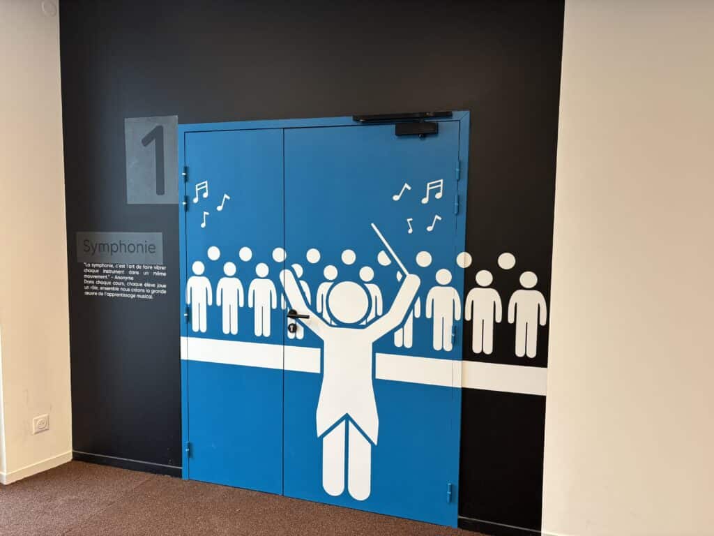 Porte décorative Symphonie : chef d'orchestre et chœur Porte bleue Symphonie avec pictogrammes blancs d'un chef d'orchestre et d'un chœur sur fond noir.